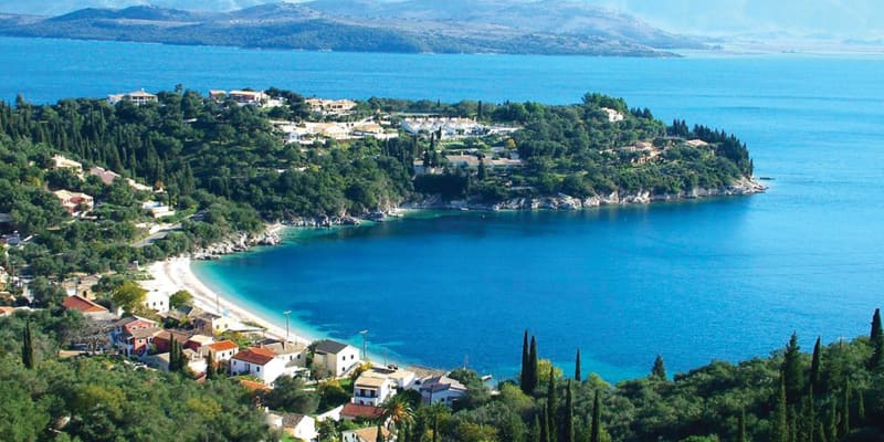 kalami bay from above - azure blue water and white sands frame by slight hills with quaint building and and lush green shrubbery